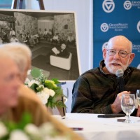 Man sitting down at table hold microphone while he talks